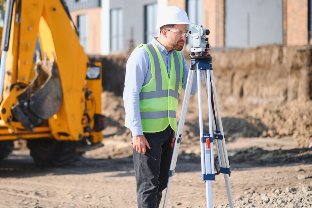 Engineer,Wearing,Hard,Hat,And,Safety,Vest,Performing,Land,Surveying